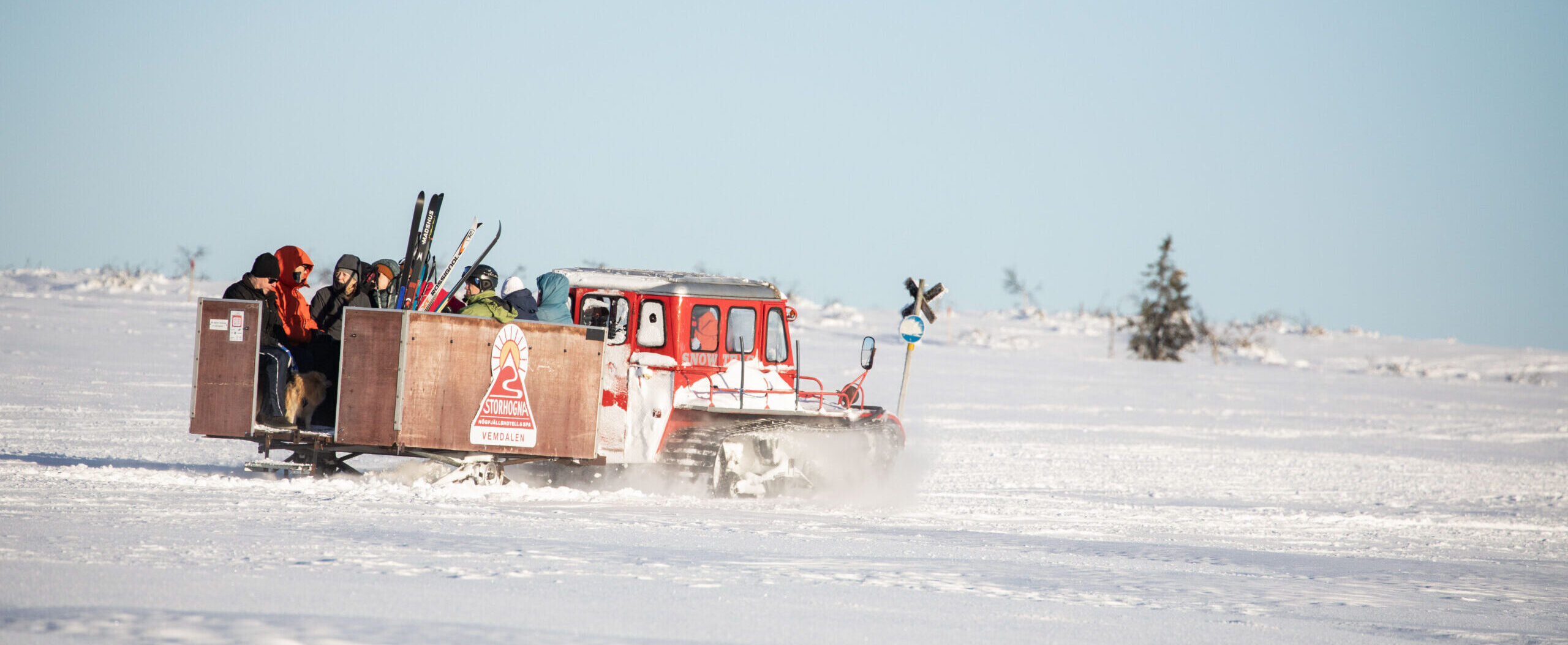 Röd vessla med släp kör över snötäckt fjäll