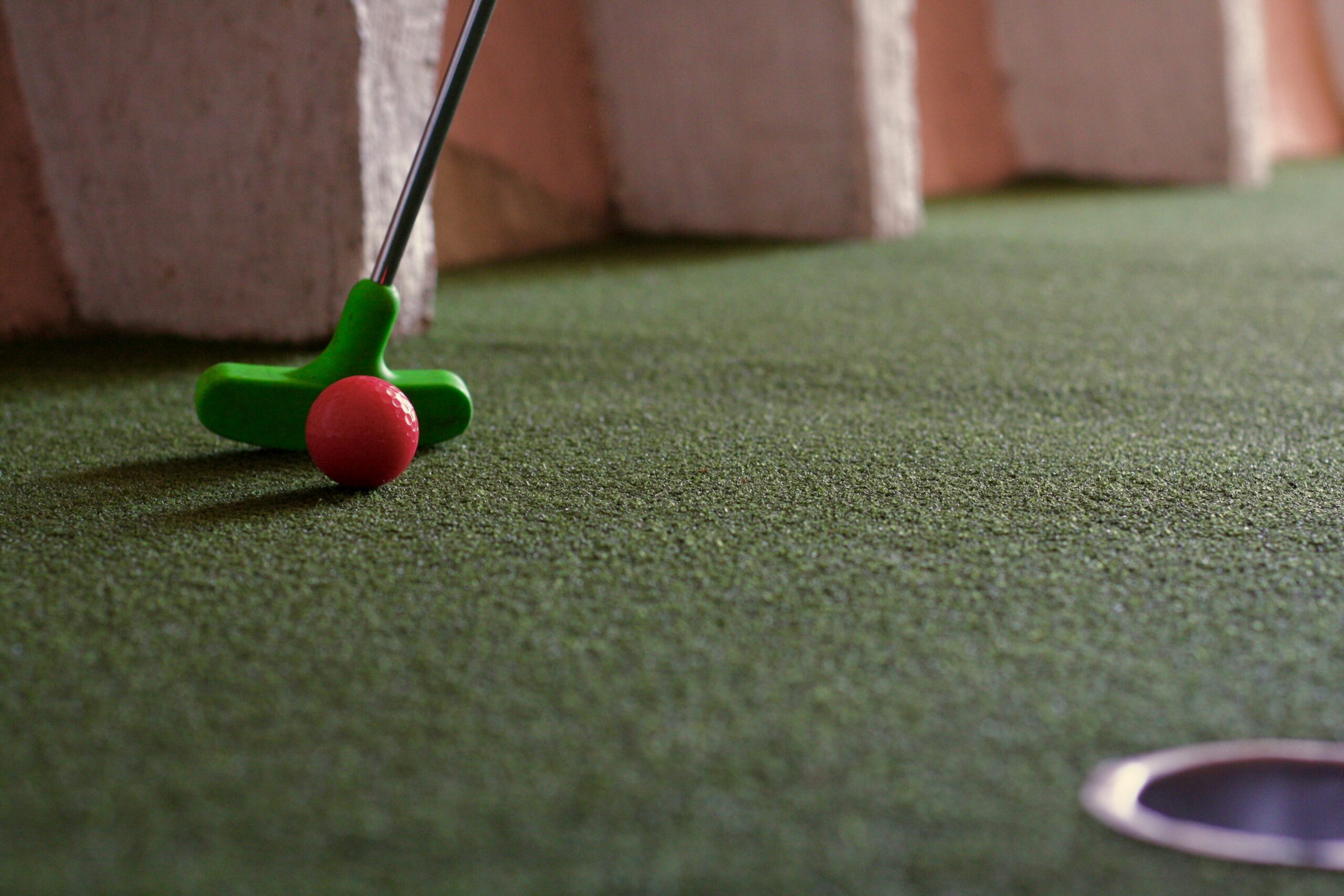 Minigolfklubba och boll på en grön minigolfbana