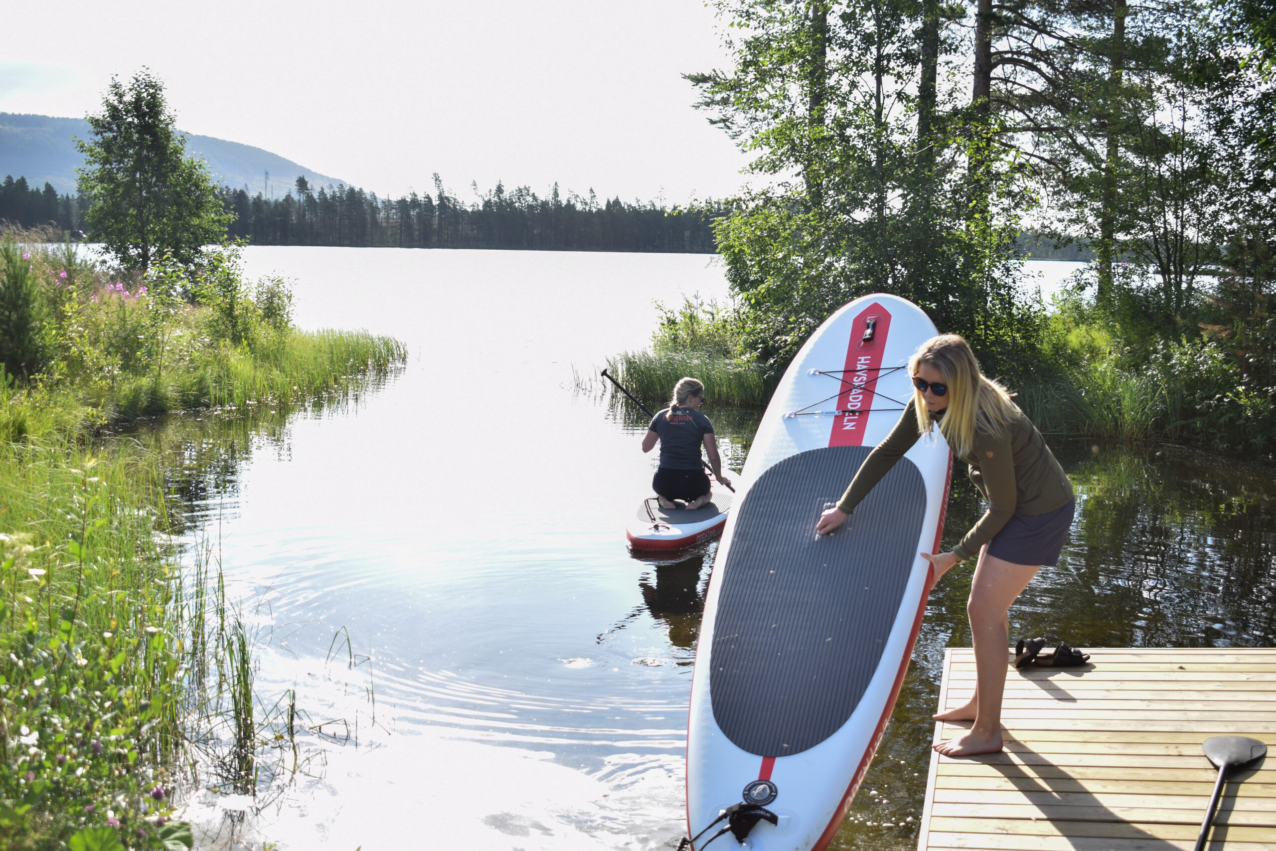 SUP-bräda vid en brygga intill en stilla sjö